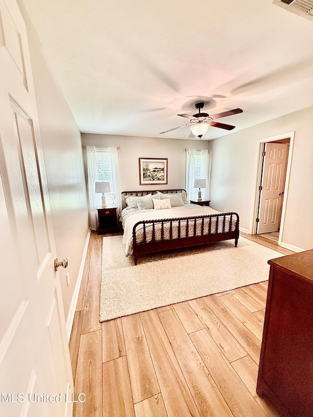 bedroom with visible vents, a ceiling fan, light wood-style flooring, and baseboards