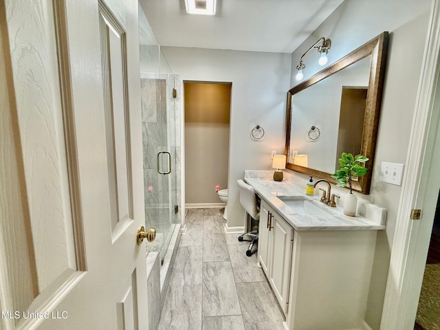 full bath featuring vanity, toilet, marble finish floor, baseboards, and a stall shower