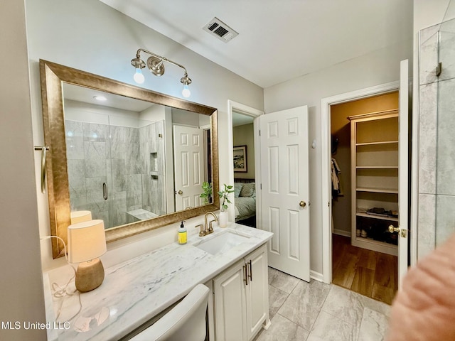 ensuite bathroom featuring visible vents, a stall shower, vanity, a spacious closet, and ensuite bathroom