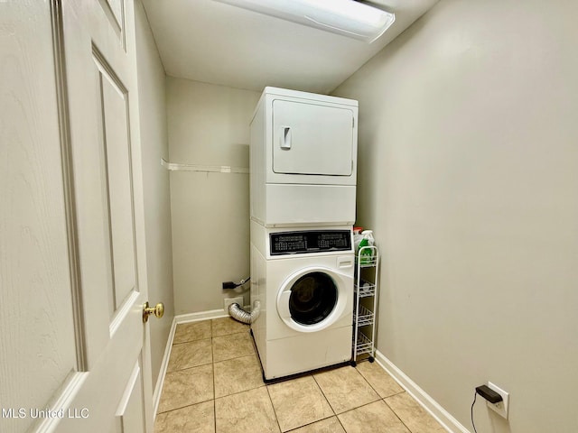 laundry area with laundry area, baseboards, stacked washing maching and dryer, and light tile patterned flooring
