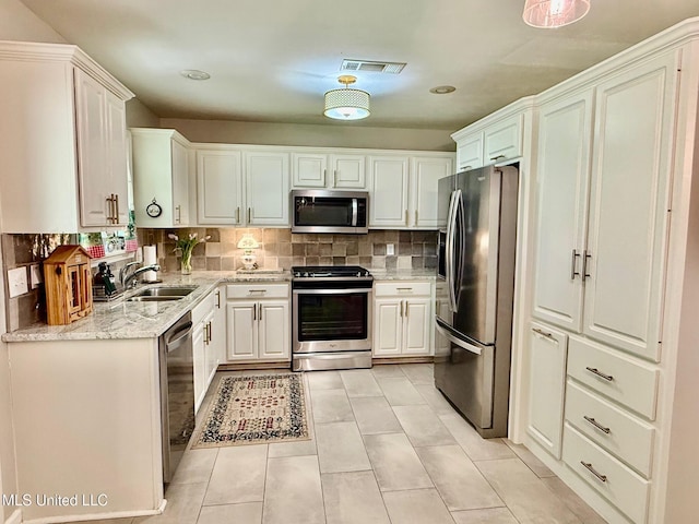 kitchen featuring visible vents, light tile patterned floors, a sink, backsplash, and stainless steel appliances