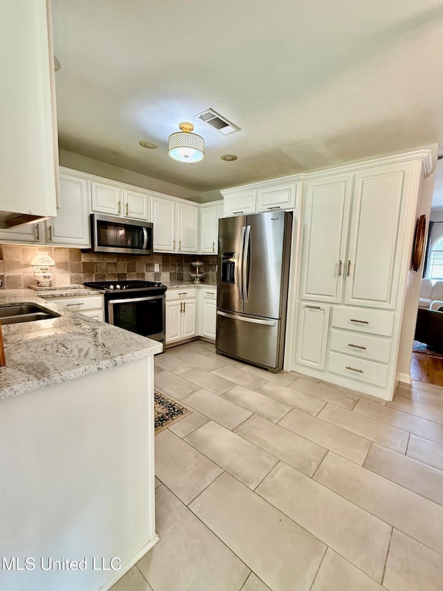 kitchen with white cabinets, a sink, stainless steel appliances, backsplash, and visible vents