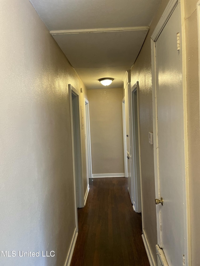 corridor with dark wood-type flooring and baseboards