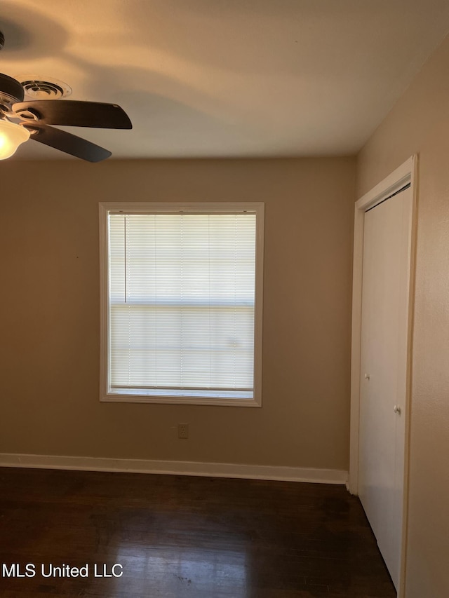 unfurnished bedroom featuring a closet, a ceiling fan, baseboards, and dark wood-style flooring