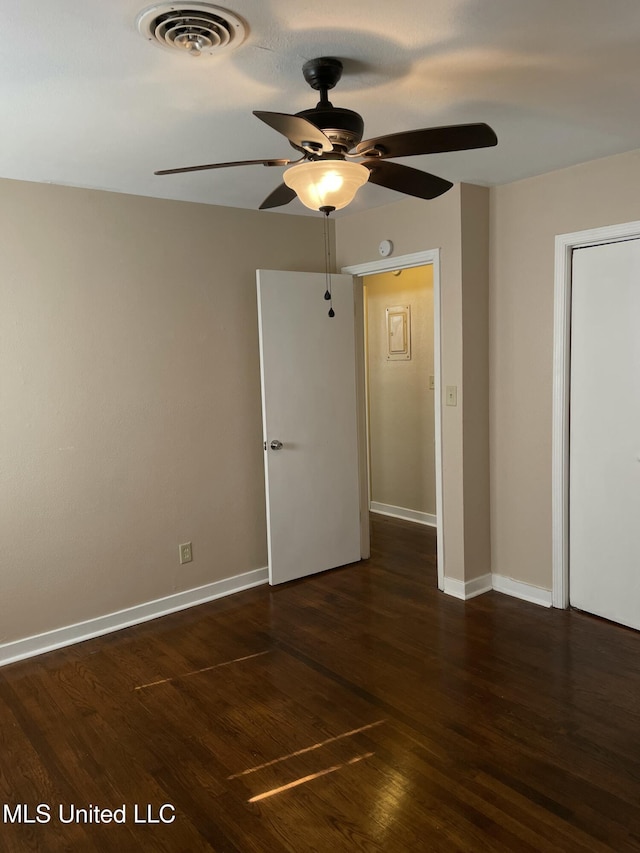 unfurnished bedroom featuring a ceiling fan, dark wood-type flooring, baseboards, and visible vents