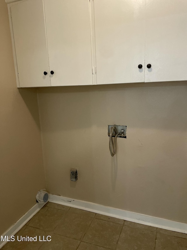 clothes washing area featuring cabinet space, hookup for a washing machine, baseboards, and dark tile patterned flooring