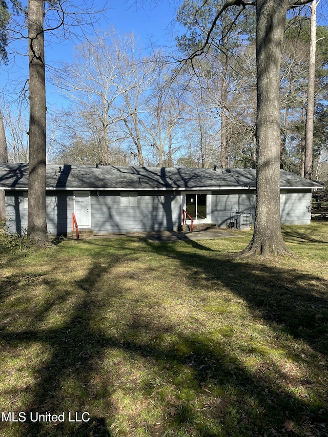 back of property featuring entry steps and a lawn