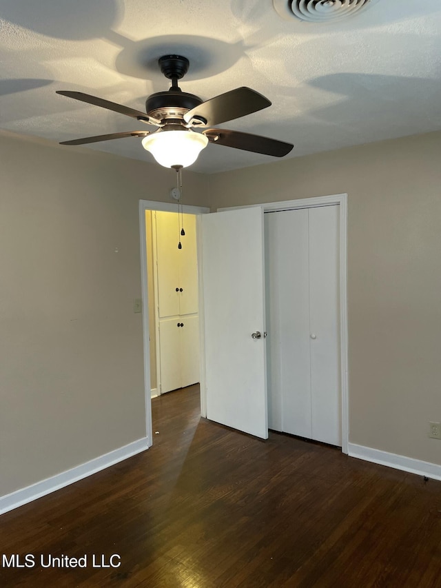 unfurnished bedroom featuring a closet, visible vents, baseboards, and wood finished floors