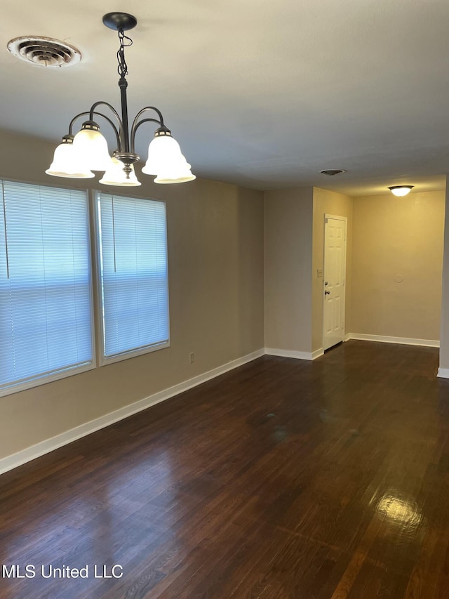 empty room with dark wood-style floors, visible vents, a notable chandelier, and baseboards