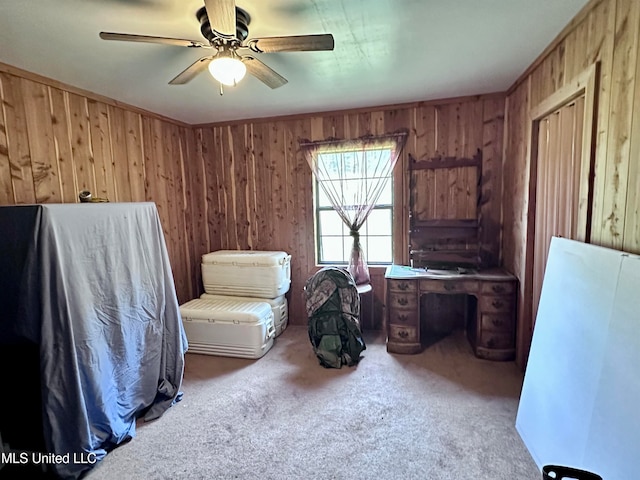 interior space with carpet floors, wooden walls, and ceiling fan