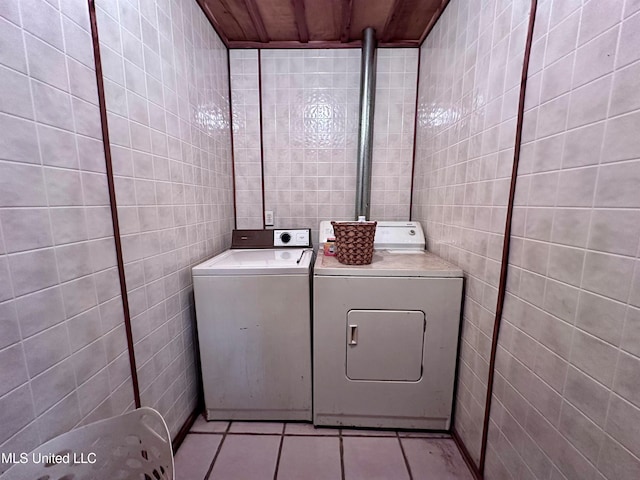 washroom with tile walls, separate washer and dryer, and light tile patterned floors