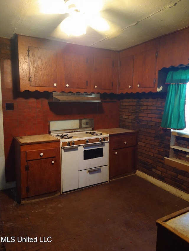 kitchen with white range with gas cooktop, brick wall, exhaust hood, and ceiling fan