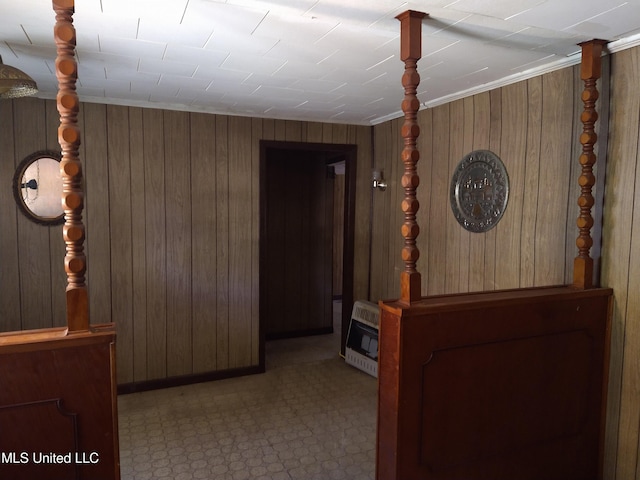 hallway with crown molding, wood walls, and heating unit