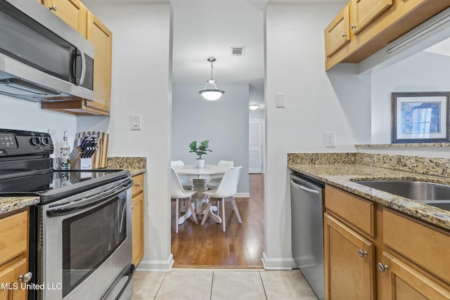 kitchen featuring stainless steel appliances, visible vents, light stone counters, and light tile patterned floors