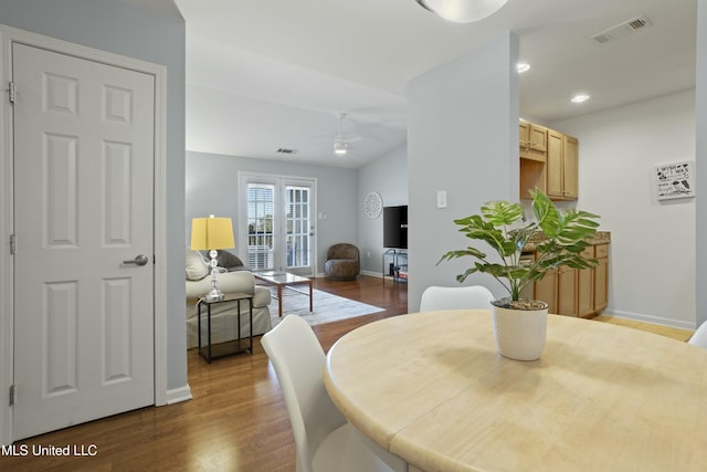 dining area featuring lofted ceiling, visible vents, a ceiling fan, wood finished floors, and baseboards