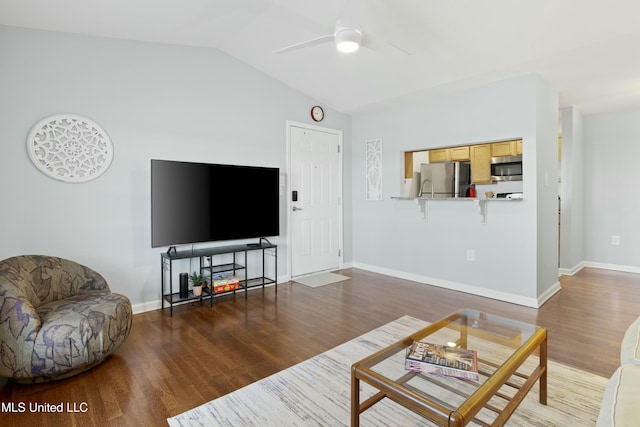 living area featuring baseboards, a ceiling fan, vaulted ceiling, and wood finished floors