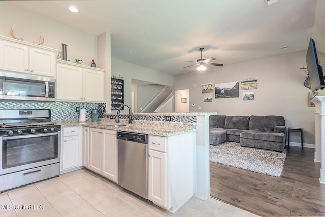 3289 Marion Ln, Southaven, MS 38672 - kitchen with stainless steel appliances, open floor plan, a peninsula, ceiling fan, and white cabinetry