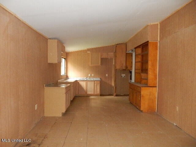 kitchen featuring lofted ceiling and wooden walls