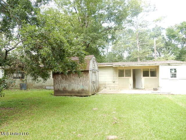 back of property featuring a shed and a lawn