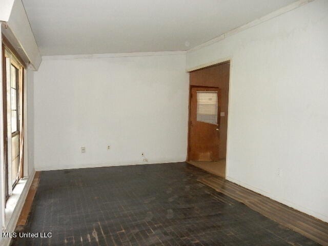 empty room featuring ornamental molding and dark wood-type flooring