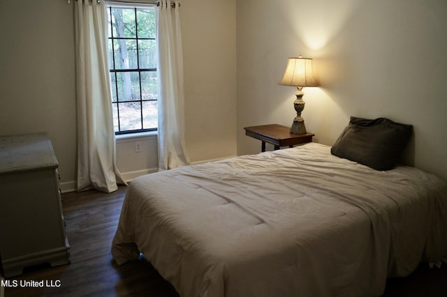 bedroom with multiple windows and dark hardwood / wood-style floors