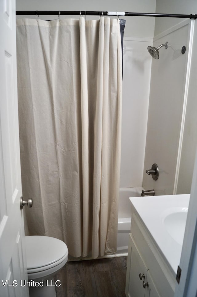 full bathroom with hardwood / wood-style floors, vanity, shower / tub combo, and toilet