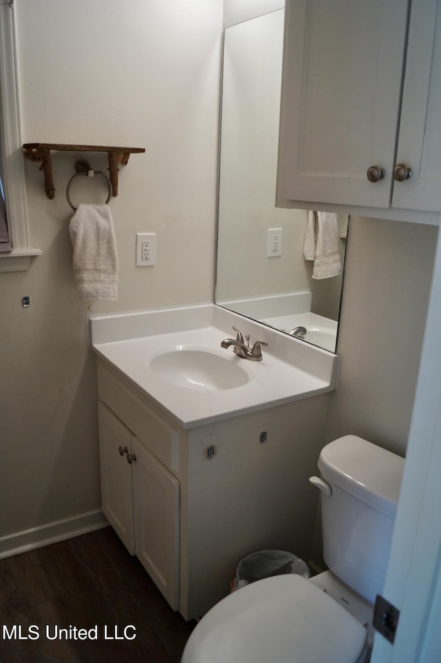 bathroom with toilet, hardwood / wood-style floors, and vanity