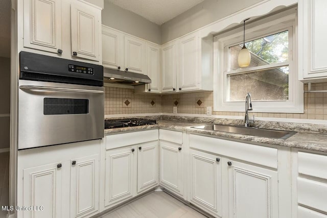 kitchen featuring oven, a sink, tasteful backsplash, black gas stovetop, and under cabinet range hood