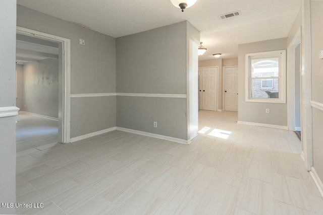 spare room with baseboards and visible vents