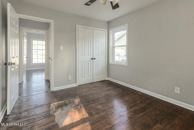 unfurnished bedroom featuring baseboards, a ceiling fan, wood finished floors, and a closet