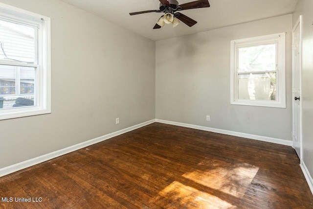 unfurnished room with dark wood-type flooring, a ceiling fan, and baseboards