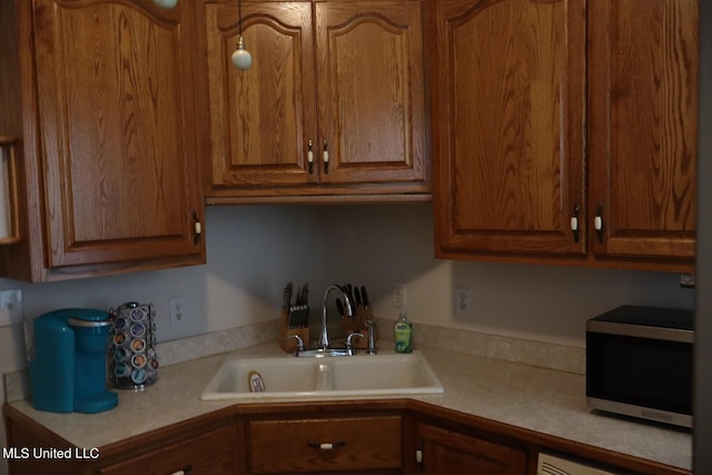 1009 Resca De La Palma St, Pascagoula, MS 39567 - kitchen with stainless steel microwave, light countertops, and brown cabinetry