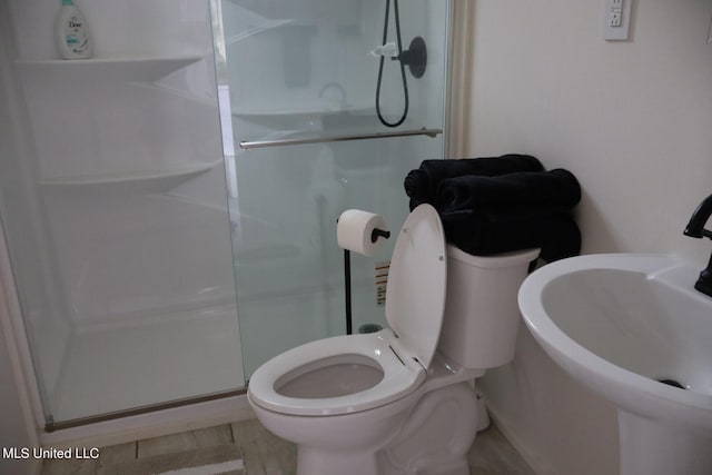 bathroom featuring a shower with door, sink, hardwood / wood-style floors, and toilet