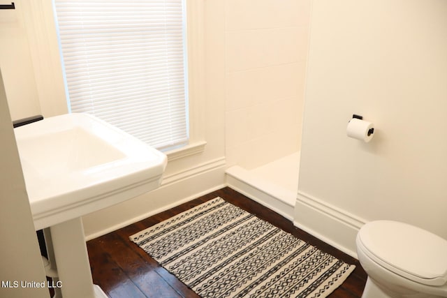 bathroom featuring hardwood / wood-style floors, a shower, and toilet