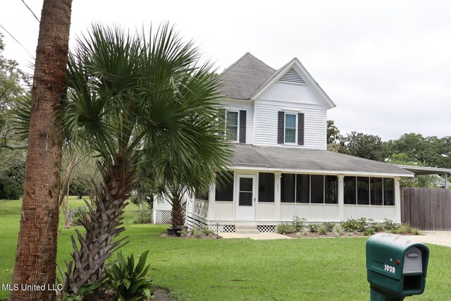 view of front of property featuring a front yard and a sunroom