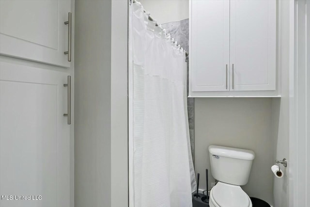 bathroom featuring a shower with shower curtain and toilet