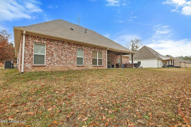 back of house featuring central air condition unit and a lawn