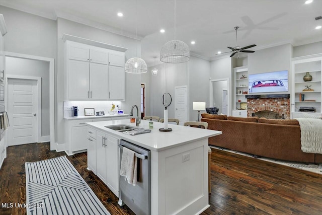 kitchen featuring sink, stainless steel dishwasher, an island with sink, pendant lighting, and white cabinets