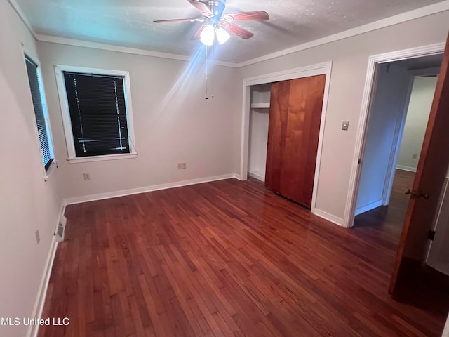 unfurnished bedroom featuring a closet, dark hardwood / wood-style floors, crown molding, and ceiling fan