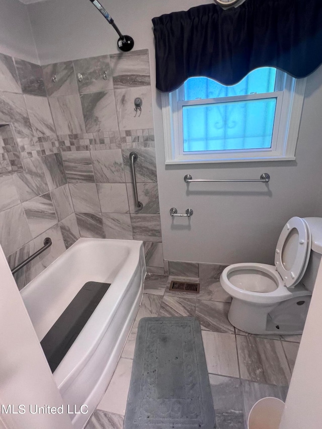 bathroom featuring toilet and tiled shower / bath