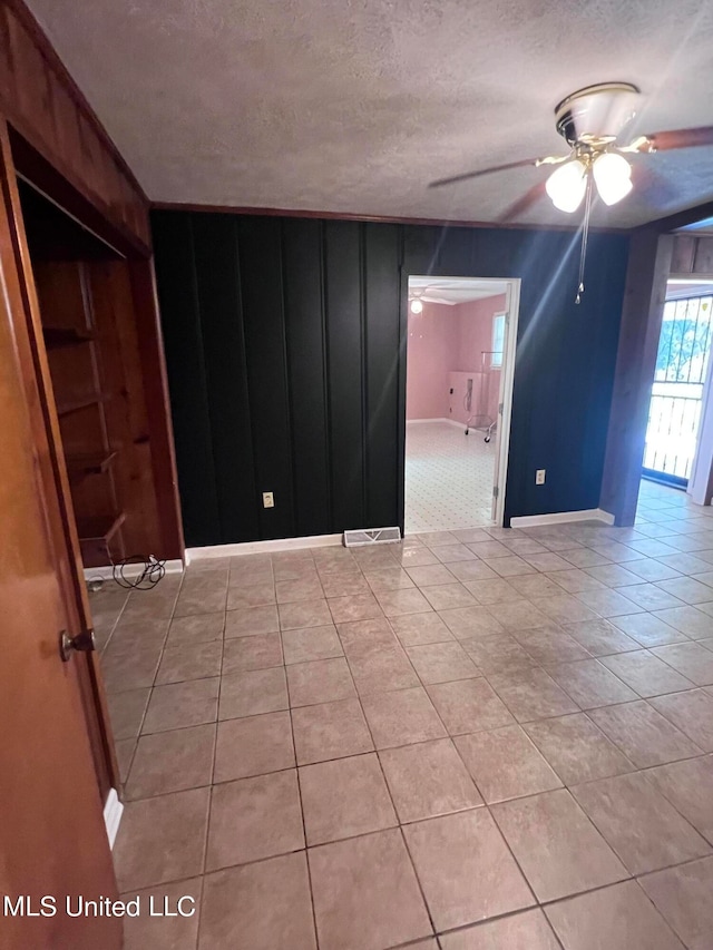 tiled empty room featuring a textured ceiling and ceiling fan