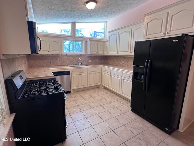 kitchen with black appliances, sink, light tile patterned flooring, a textured ceiling, and white cabinets