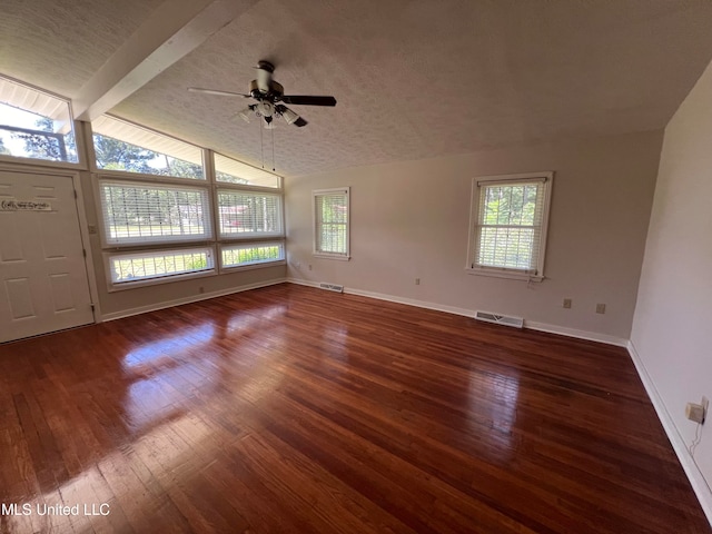 unfurnished living room with dark wood-type flooring, ceiling fan, a textured ceiling, and vaulted ceiling with beams