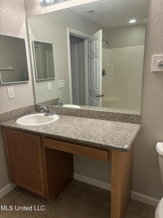 bathroom featuring tile patterned flooring, vanity, toilet, and a shower