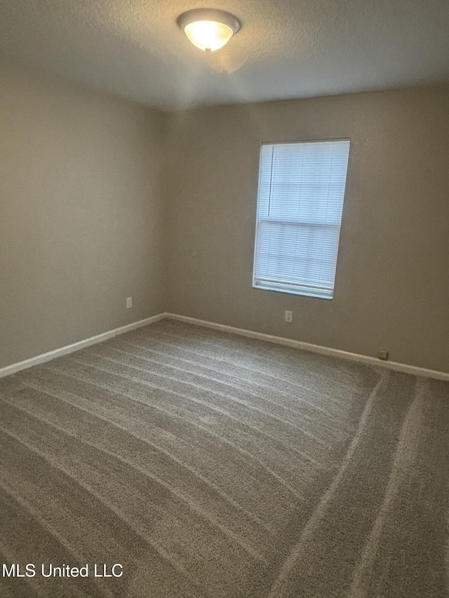 carpeted empty room with baseboards and a textured ceiling