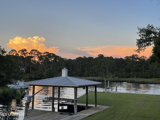 dock area with a water view, a forest view, boat lift, and a yard