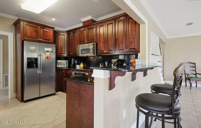 kitchen featuring a breakfast bar area, stainless steel appliances, a peninsula, tasteful backsplash, and crown molding