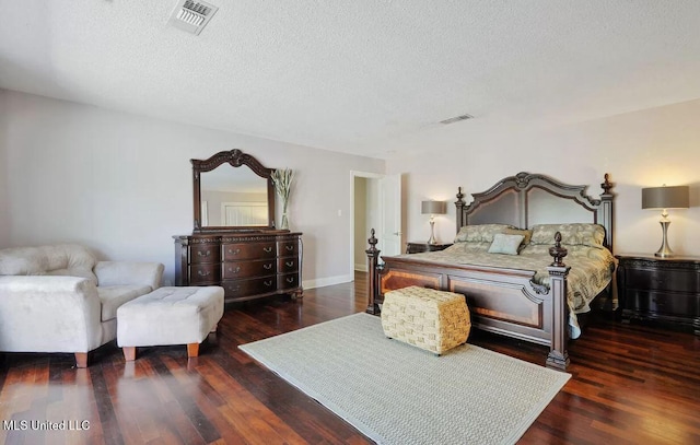 bedroom with a textured ceiling, wood finished floors, visible vents, and baseboards