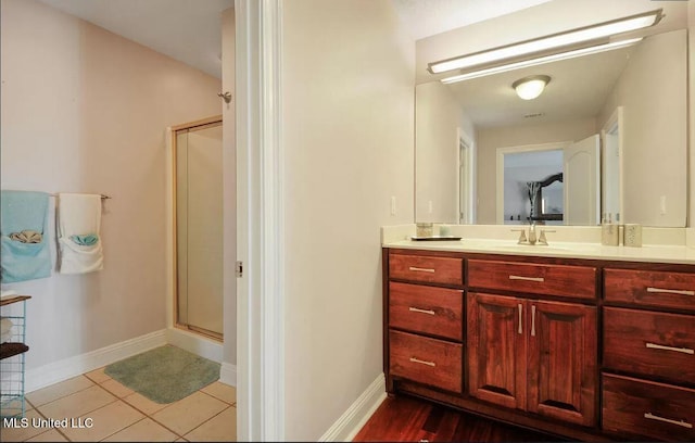 full bathroom with a stall shower, tile patterned flooring, baseboards, and vanity