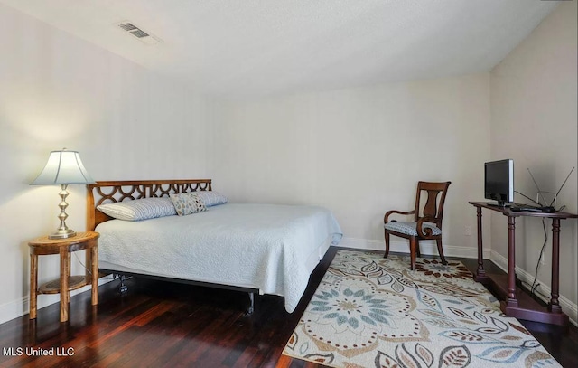 bedroom with wood finished floors, visible vents, and baseboards